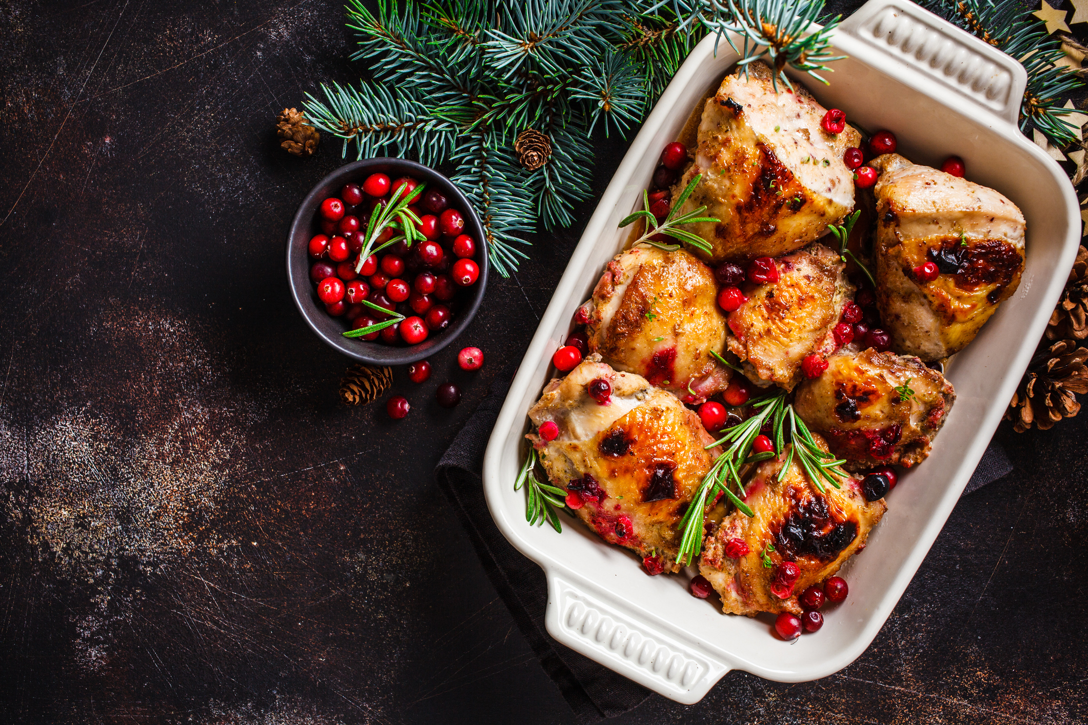 Christmas food. Baked Chicken meat with cranberries and rosemary in the oven dish, dark background, copy space.
