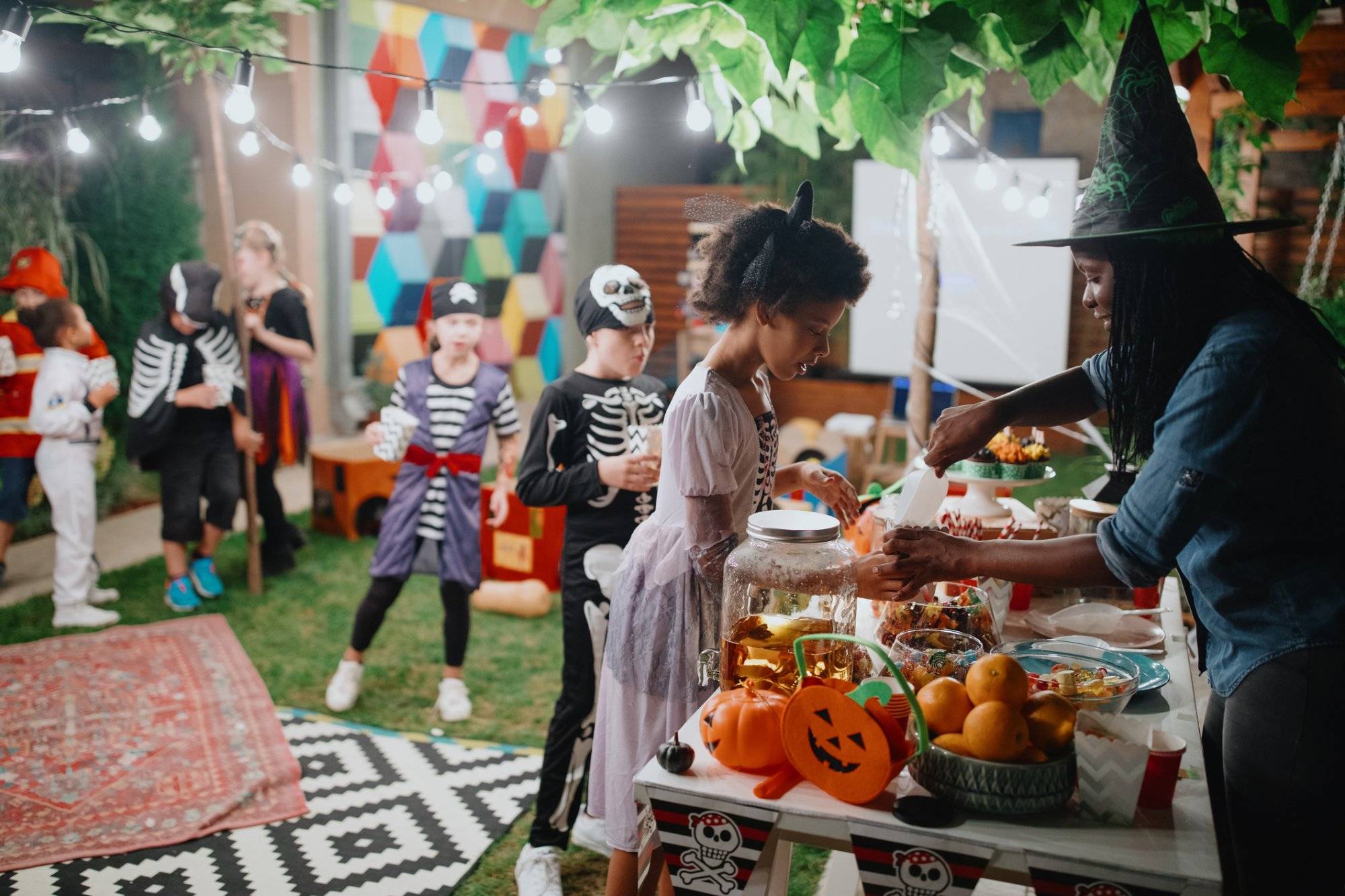 Parent serving candy and popcorn to her kids and their friends at backyard movie night