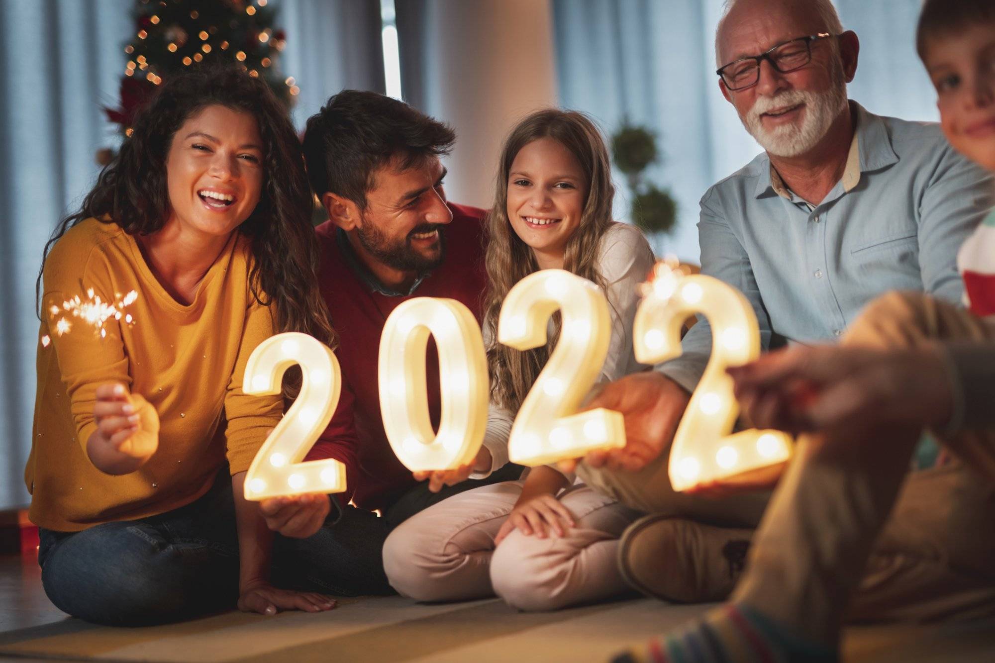 Family holding illuminative numbers 2022 while celebrating New Year