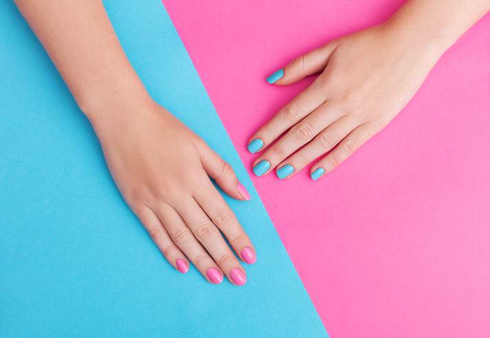 Closeup of hands of a young woman with manicure on nails against pink background Closeup of hands of a young woman with manicure on nails against pink background