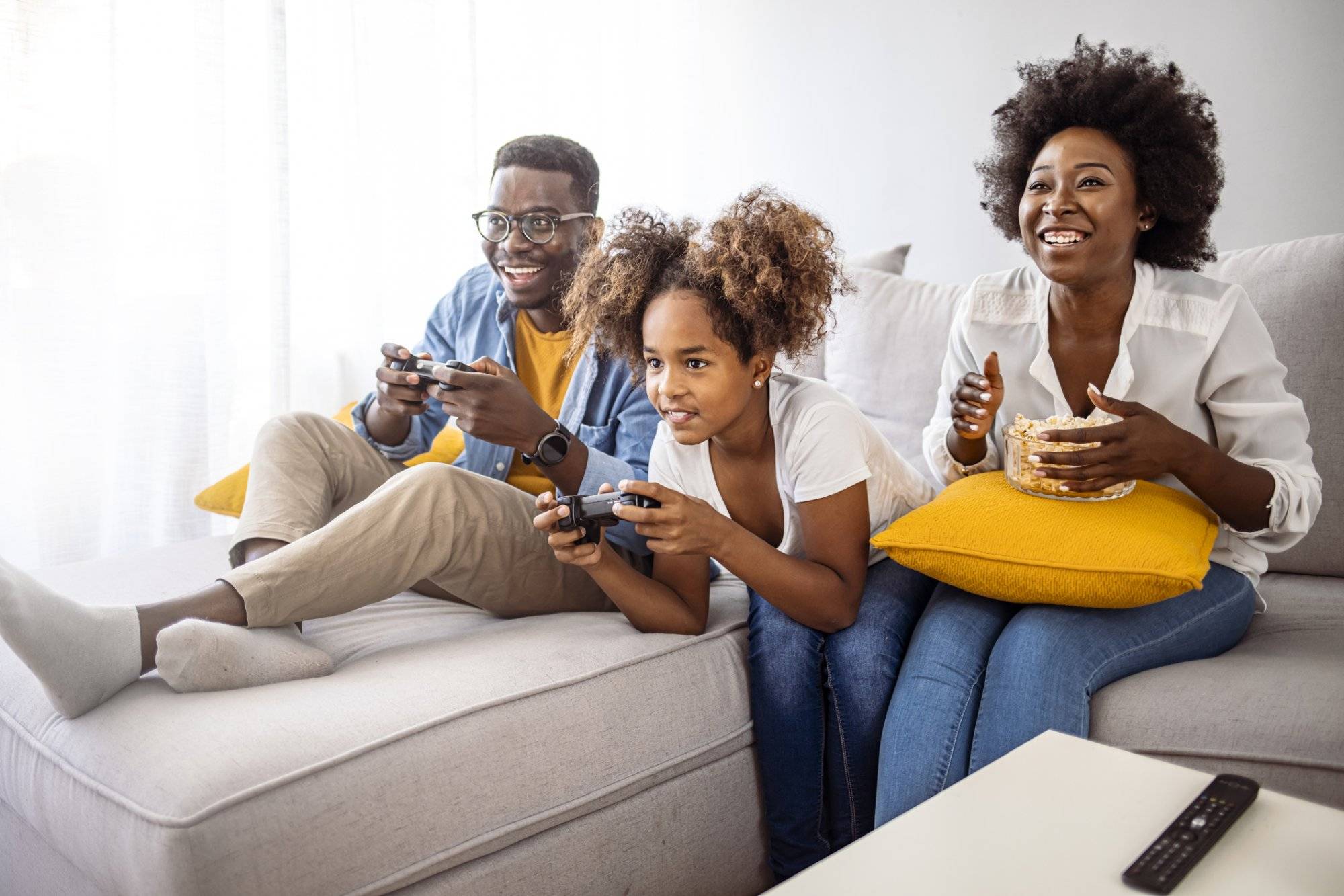 Smiling family sitting on the couch together playing video games Smiling family sitting on the couch together playing video games